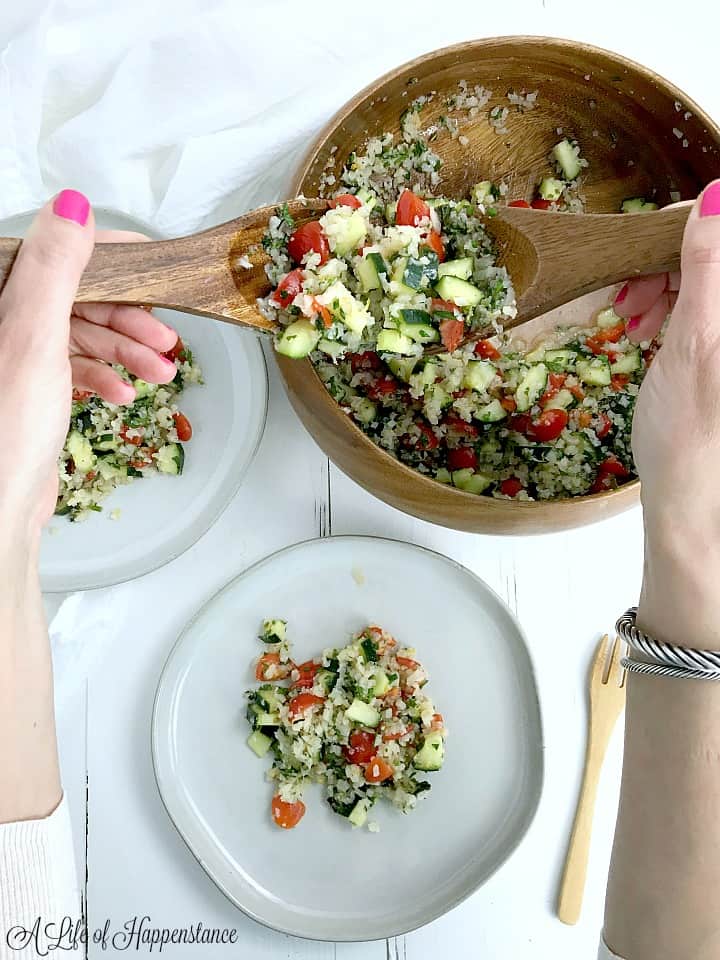 Scooping tabbouleh out of a bowl and onto plates. 