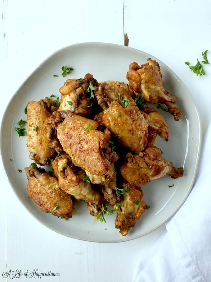 Easy Instant Pot chicken wings on a white plate sprinkled with parsley. 