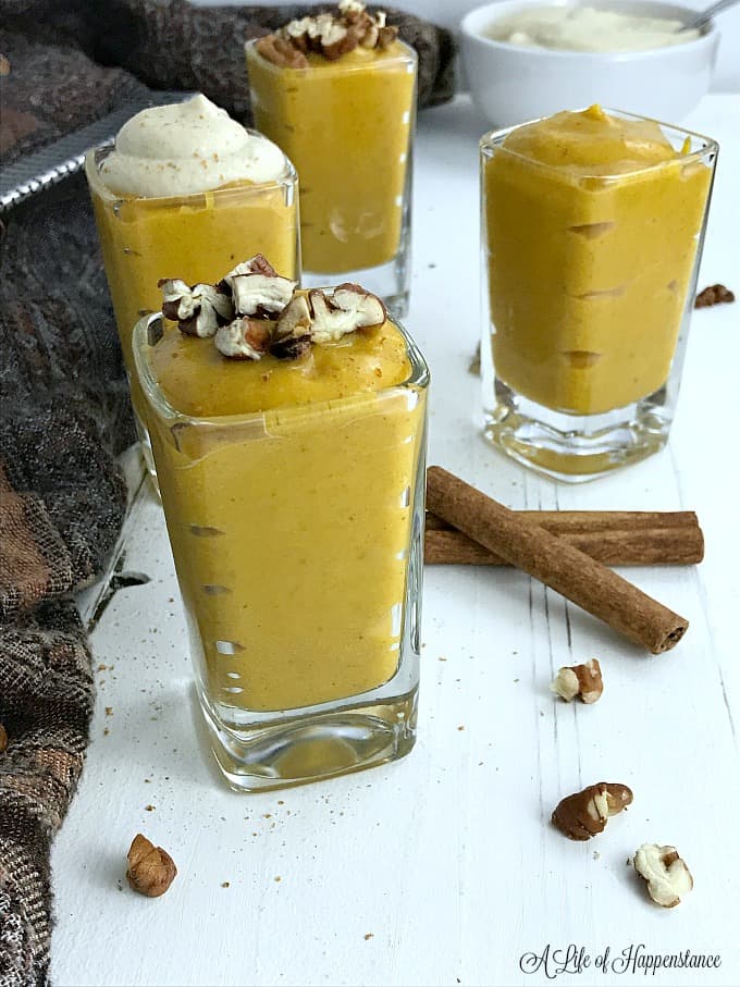 Dairy free pumpkin pudding in small glasses topped with nuts and cashew cream 