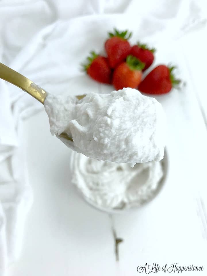 A gold spoon with coconut whipped cream on it. 