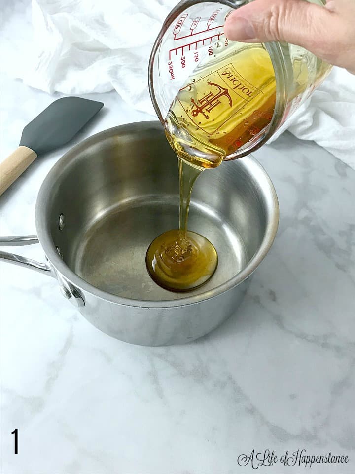 Pouring honey from a measuring cup into a saucepan. 