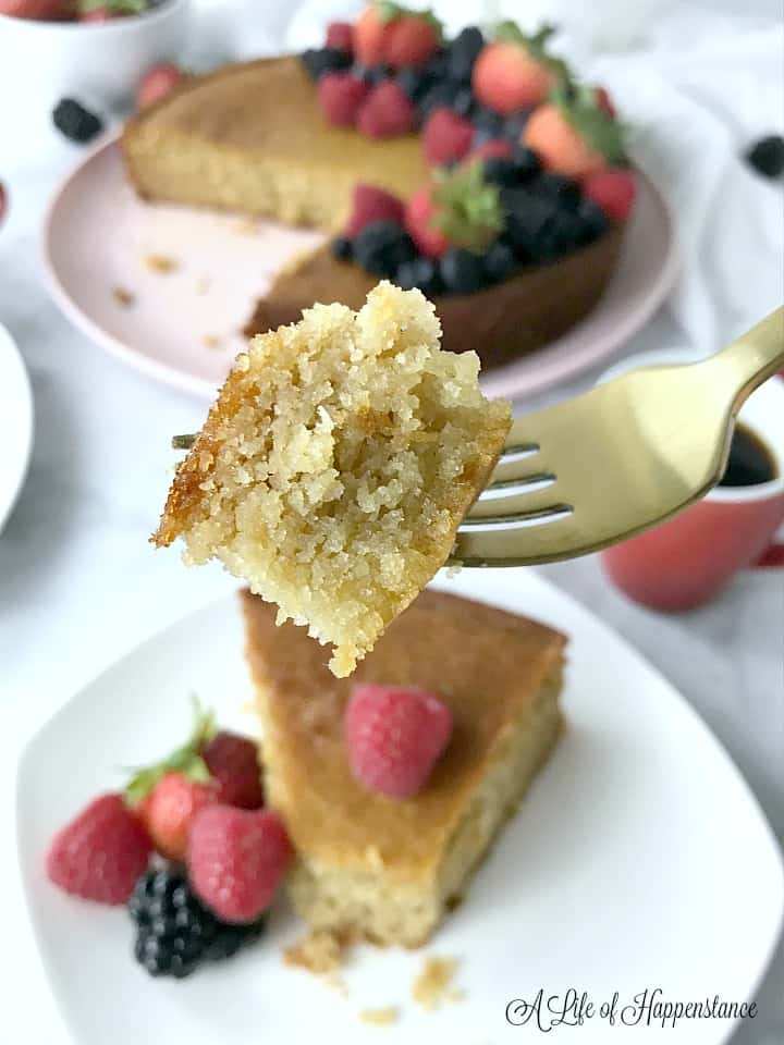 An up close photo of a forkful of almond flour cake with the rest of the dessert in the background. 