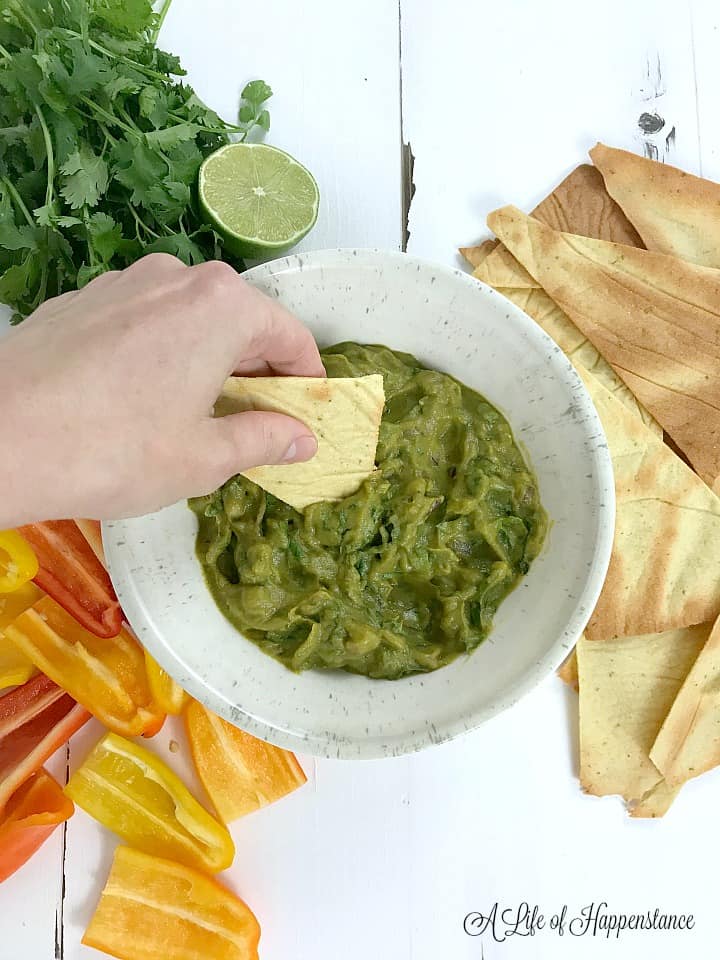 Dipping and almond flour chip into a bowl of broccomole. 