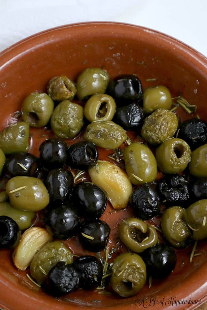 Roasted olives in an oven safe brown baking dish. 