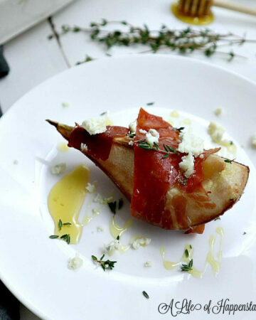 A prosciutto wrapped pear on a white plate.