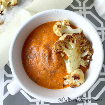 A bowl of soup garnished with roasted cauliflower florets.