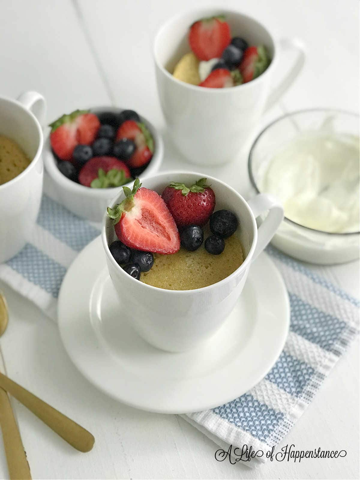 Almond flour vanilla mug cake in a white mug garnished with fresh berries. 
