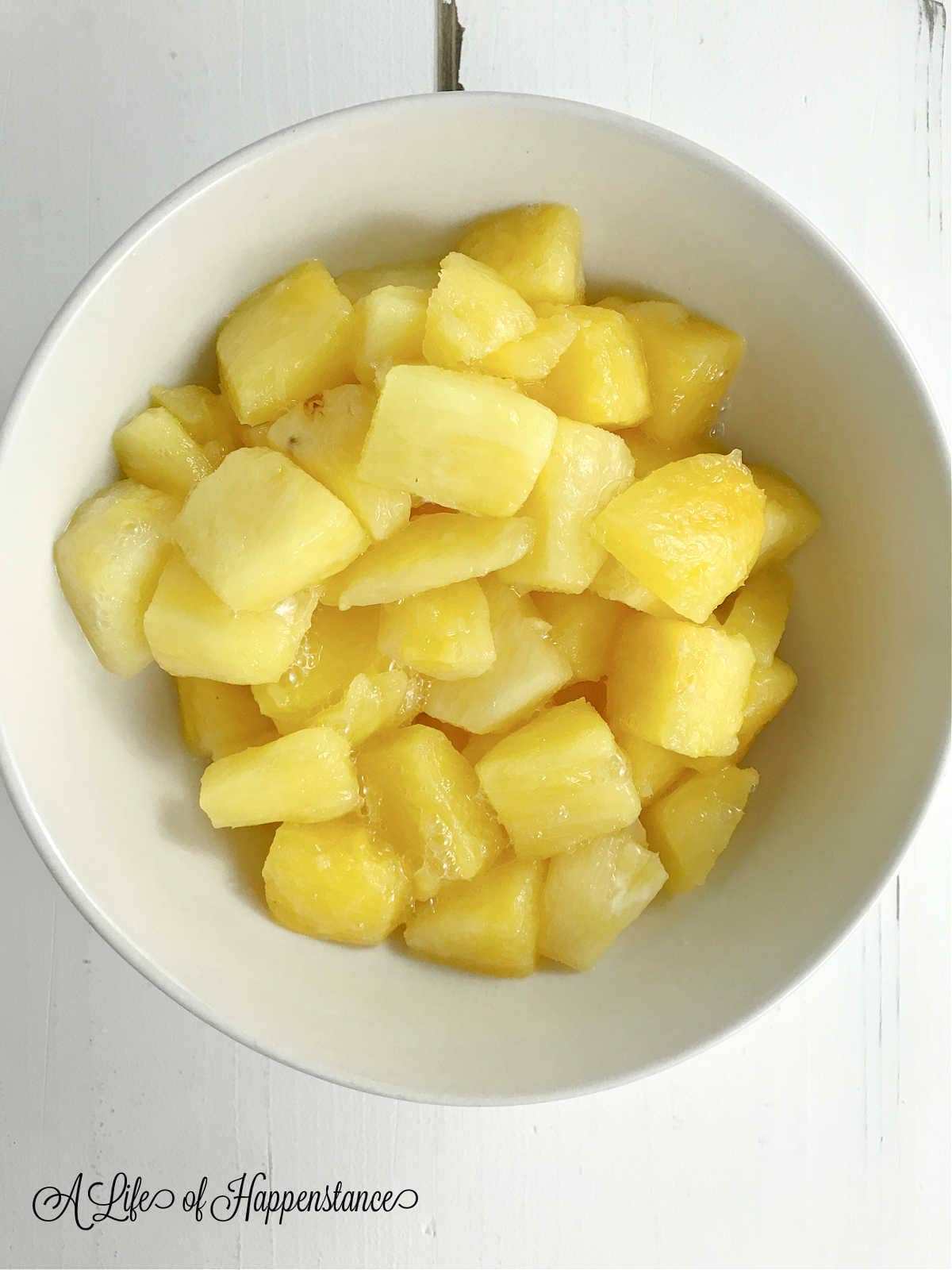 Chopped pineapple in a white bowl.