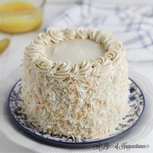 The decorated almond coconut cake on a white and blue flower plate.