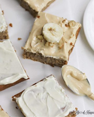 The cut frosted banana bars on a white table and spoonful of peanut butter frosting.