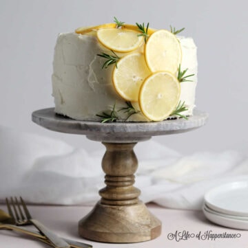 A lemon rosemary cake on a cake stand.