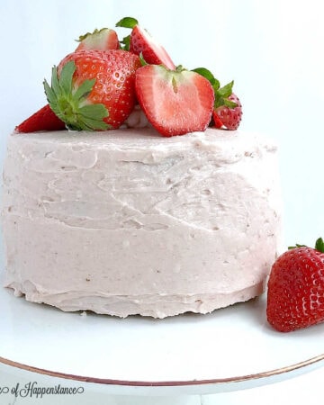 A strawberry almond flour cake on a white cake stand.