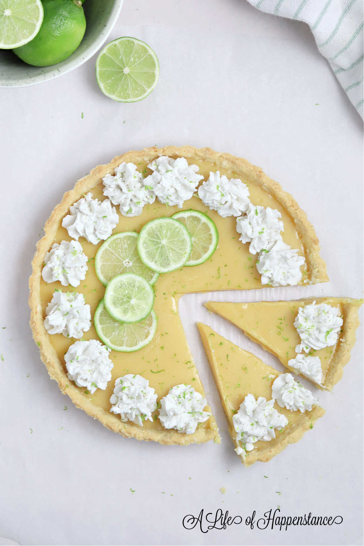 A coconut lime tart on a table with two slices cut from it.